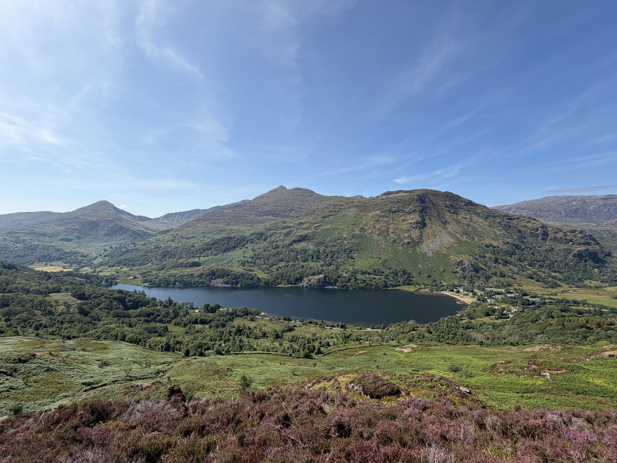 A lake beneath green mountain slopes on a clear summer day